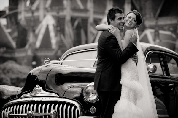 Adorable bride and groom hug in front of limousine - wedding photo by Jerry Ghionis